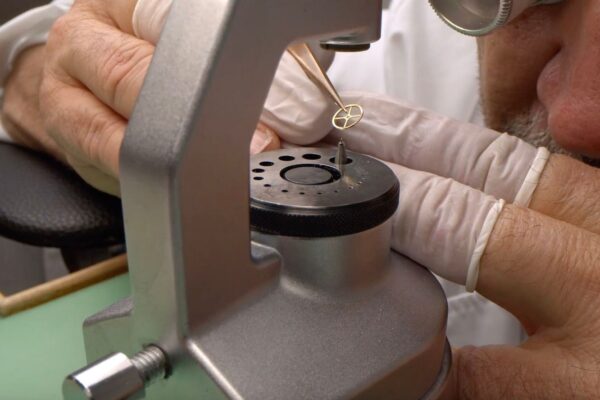 Watchmaker performing modern micro-regulation on a mechanical watch balance wheel